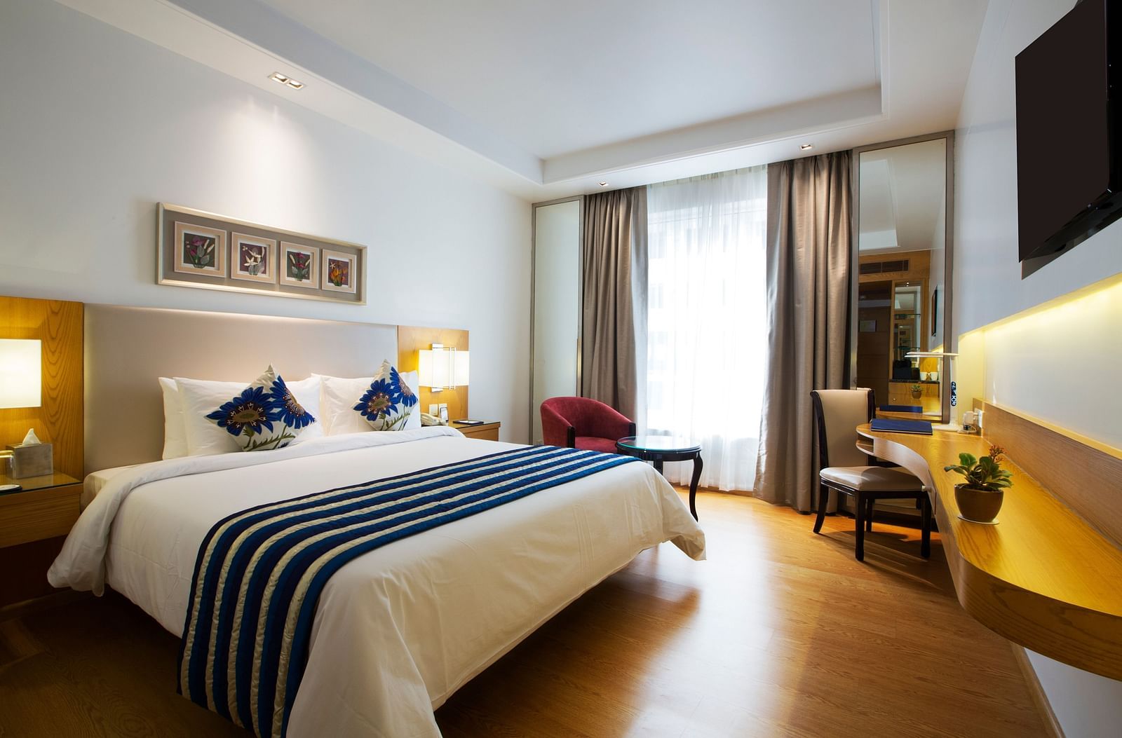 A bedroom with cosy and modern interiors featuring a double bed along with wooden flooring - Ramada by Wyndham, Ghaziabad, Vasundhara