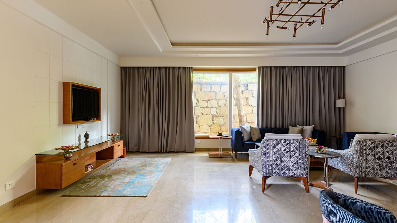 The living room of our Presidential Suites in Pushkar with a sofa set, a television and a large window PS-42