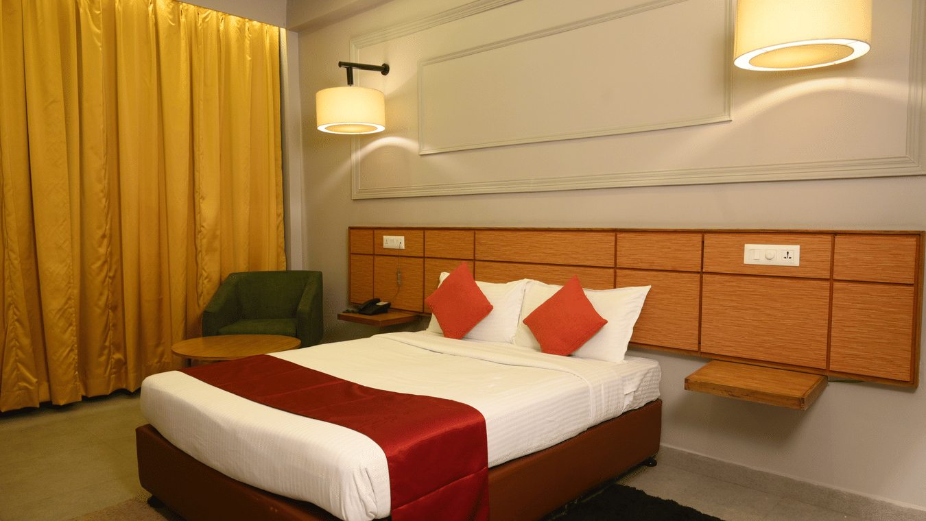 A double bed with lamps over it inside one of the rooms - Max hotel Prayagraj