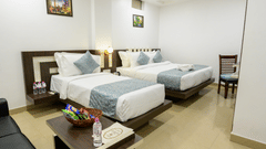 Side view of Family Room featuring two beds of different sizes, a central bed lamp, and stylish interior design at Biznotel by Pride, Deoghar.