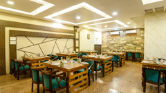 Side view of the restaurant featuring stylish interior design and table arrangements at Biznotel by Pride, Deoghar
