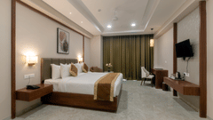 A double bed with a tv opposite it inside Deluxe room - VITS Satyajeet Karad