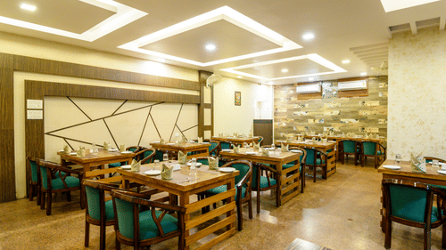 Side view of the restaurant featuring stylish interior design and table arrangements at Biznotel by Pride, Deoghar