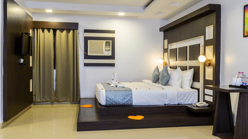 Side view of Suite Room with cosy bed, bedside light, and stylish interior design at Biznotel by Pride, Deoghar.