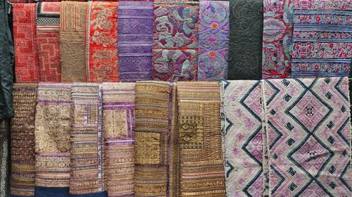 A close up of various textiles kept on a hanger to be sold inside a shop.