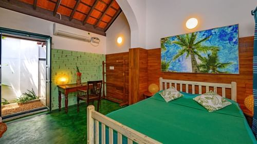 queen room with king size bed and green bed sheets 