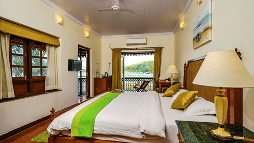 A double bed lamp on the marble side table and entrance to Olivia - River View room at neemrana s three waters