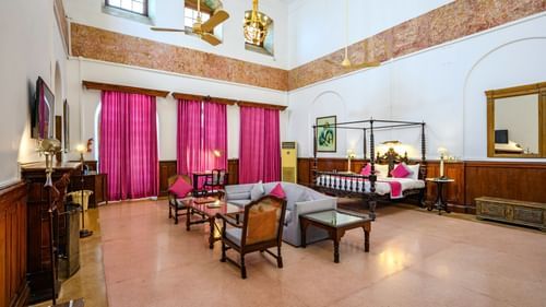 An overview of the Raja Sardul Singh room with sofas, coffee table in front of the tv with king size bed in the background - The Baradari palace