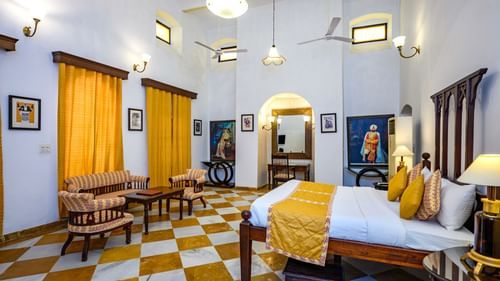 An overview of the Maharaja Amrinder Singh room with a double bed, sofas in front of the bed and a small hanging light - The Baradari palace