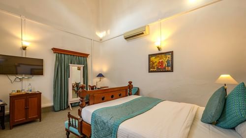 a double bed with a sofa in front of it, tv mounted to the wall and ac on the side inside Maharani Bakhtawar Kaur - The Baradari Palace