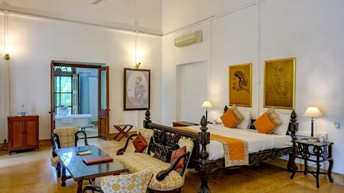 An overview of the Maharaja Sahib Singh room with sofas, coffee table in front of the tv with king size bed in the background - The Baradari palace