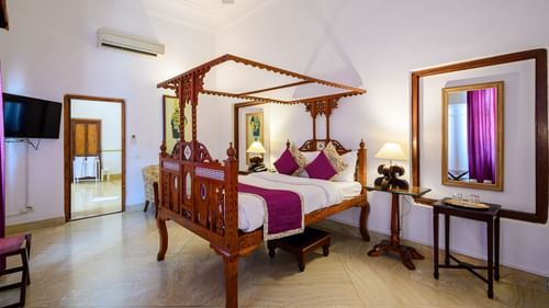 An overview of the Rani Fateh Kaur room with a double bed, mirror, and side tables - The Baradari palace