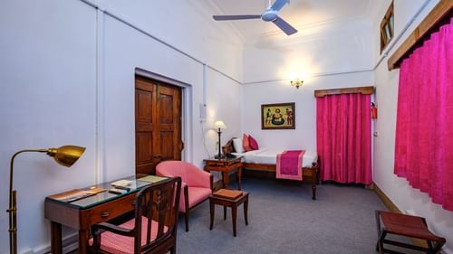 An overview of the Bibi Rajkumari Sahib Kaur room with a double bed, study table and chairs - The Baradari palace