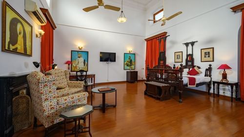 An overview of the Maharaja Moninder Singh room with single seater sofas in front of a small coffee table and a fantastically carved bed - The Baradari palace