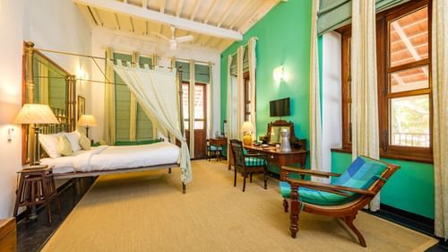 Elegant heritage-style room with vintage wooden furniture, canopy bed, and warm lighting reflecting colonial charm — perfect for those planning to stay in Tharangambadi at The Bungalow on the Beach.