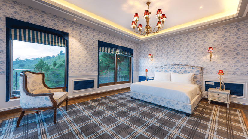 A hotel room with a large bed, ambient lighting and a vintage style chair - The Manor Luxury Hotel, Shimla