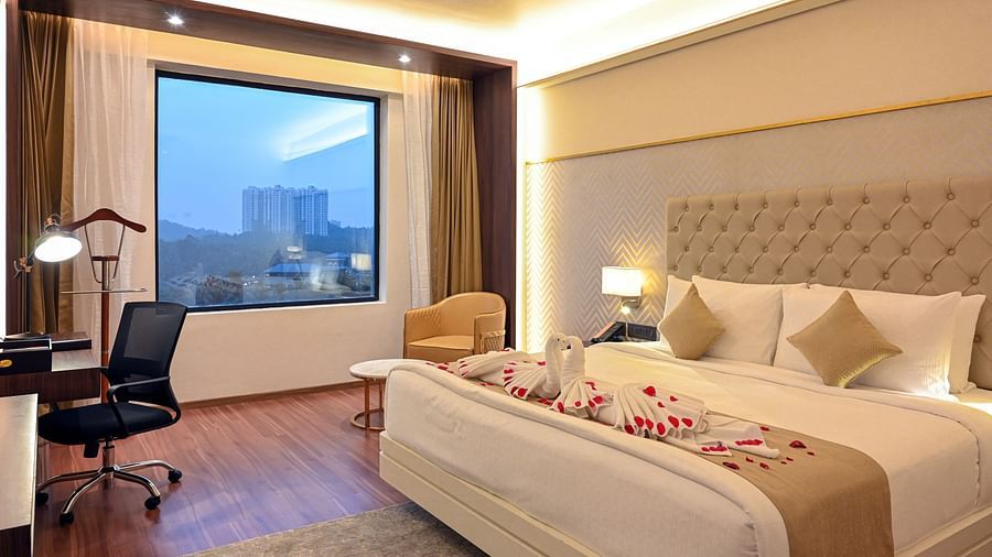 a king size bed and the work station at deluxe rooms in Calicut 3