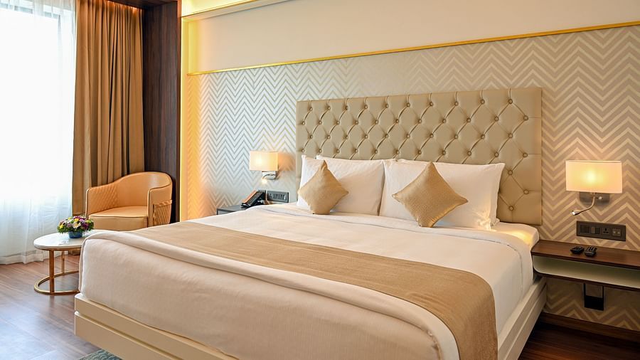 a king size bed and the work station at deluxe rooms in Calicut 4