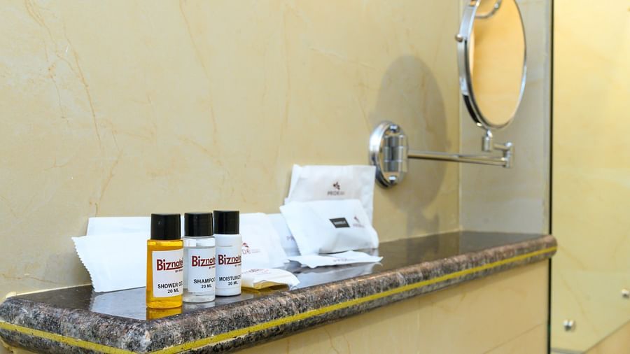 Bathroom amenities featuring shower gel, shampoo, moisturizer, and a mirror mounted on the wall.