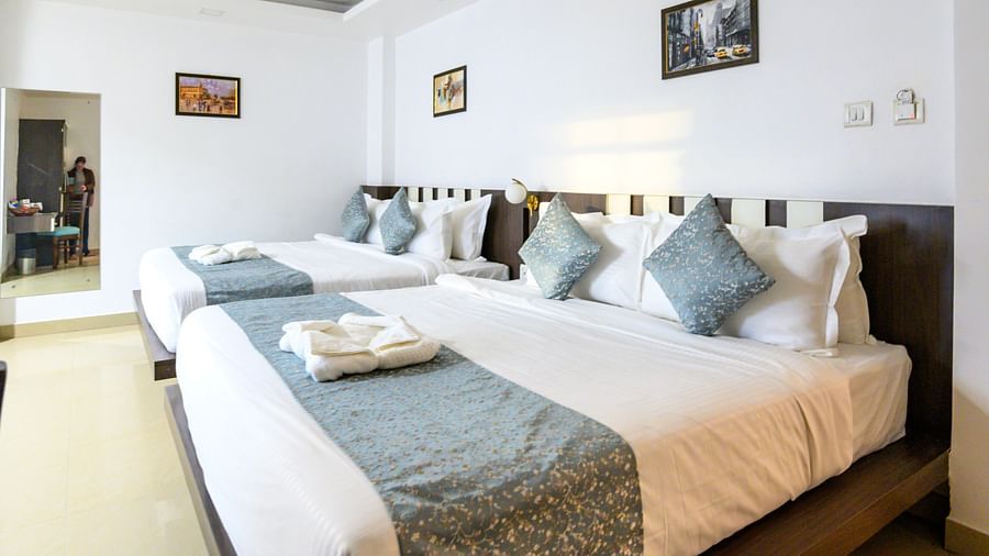 Side view of Deluxe Family Room featuring two king-sized beds and a wall-mounted mirror in the corner at Biznotel by Pride, Deoghar