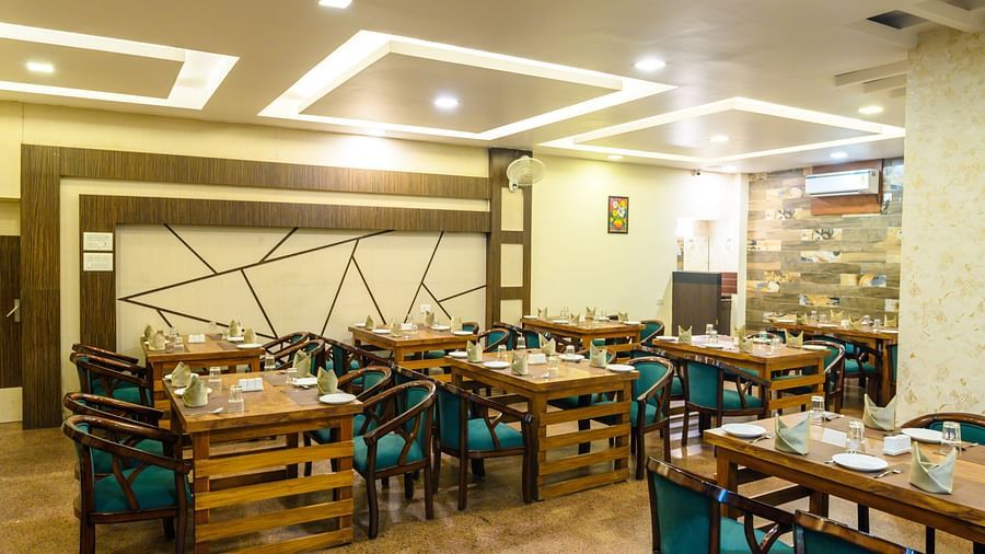 Side view of the restaurant featuring stylish interior design and table arrangements at Biznotel by Pride, Deoghar
