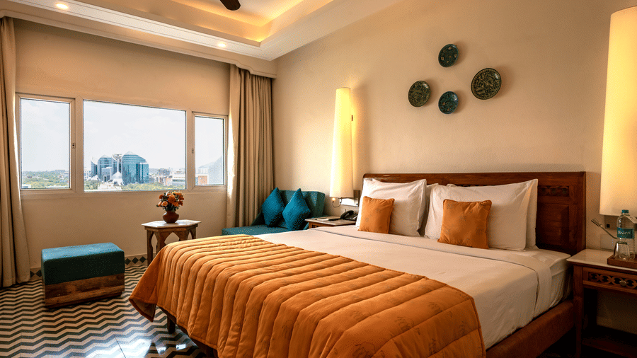 The Club room's bedroom at Clarks Group of Hotels featuring a king size bed, patterned flooring, warm lighting, seating area and city view window.