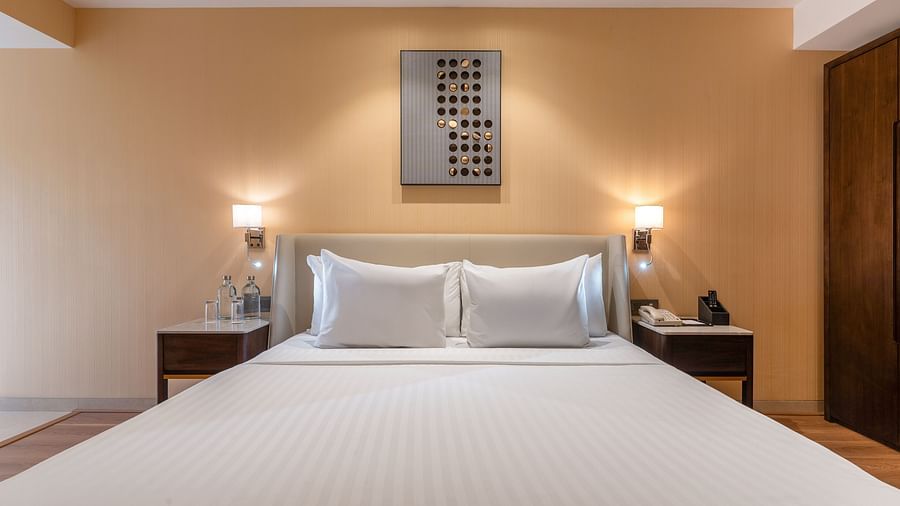  Minimalist bedroom with a double bed, bedside lamps, and warm-toned wall decor at Clarks Inn Suites, Hyderabad