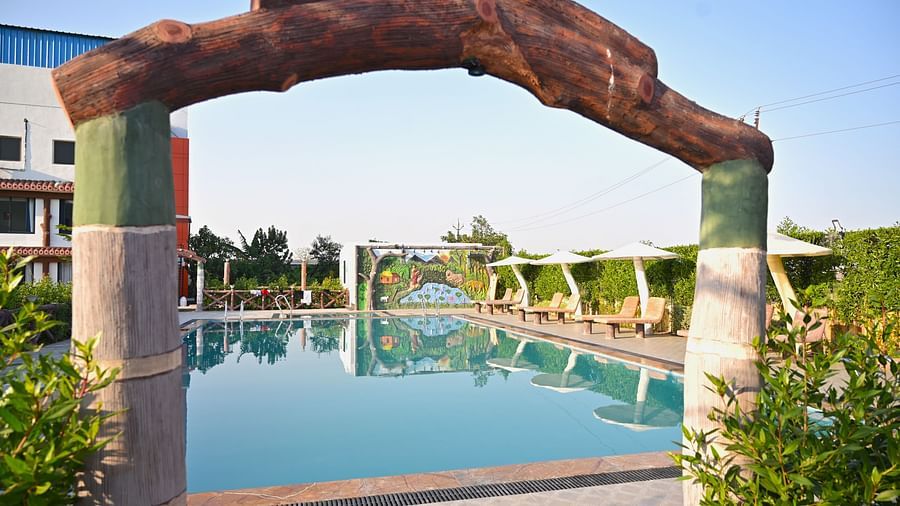 Outdoor swimming pool with relaxing beds beside at Clarks Safari Kheda, Ahmedabad