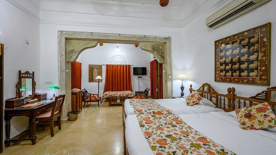 Deo Bagh - 17th Century, Gwalior - a spacious king size bed with floral pillows and bed runner on top of it at the Rohini Raja Mahal rooms in Gwalior 1