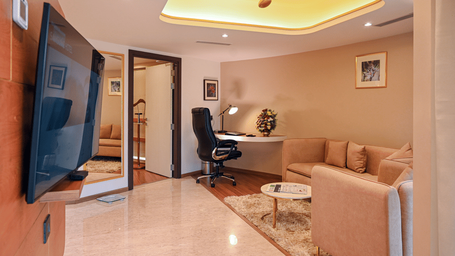 Suite living area with a comfortable sofa, work desk, and wall-mounted TV at Dimora Hotels and Resorts, offering a relaxing and functional space.