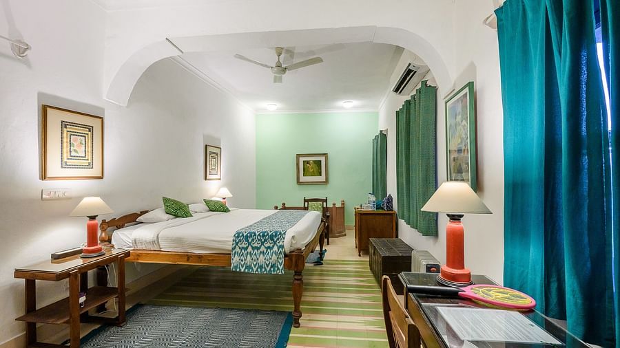 Hill Fort-Kesroli 14th Century Alwar - interior voiew of the Abhaneri Mahal - Countryside View with a king size bed, blue curtains and painitings hung on 3 walls