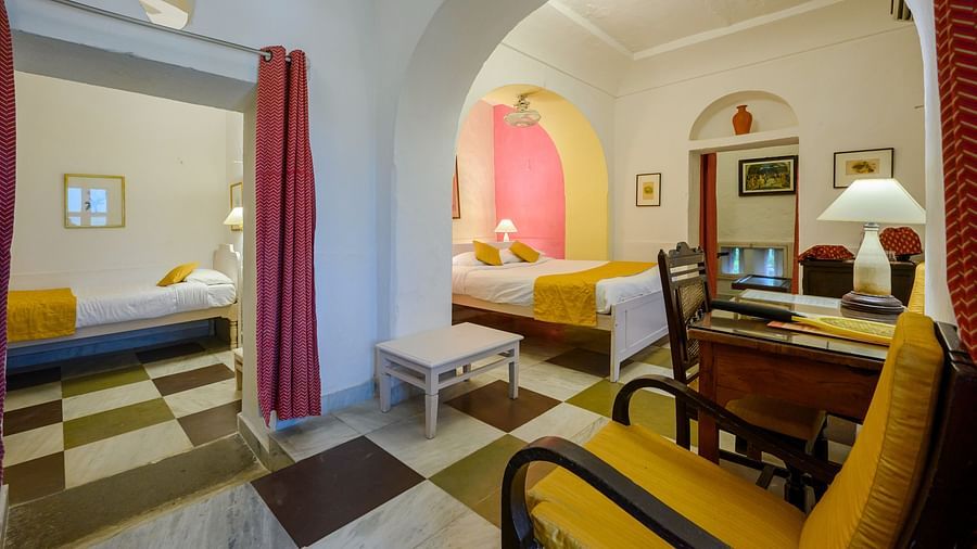 Hill Fort Kesroli 14th Century Alwar - interior view of the Raunak Mahal - Village View room featuring checkered floor, queen size bed, a chair and red curtains 