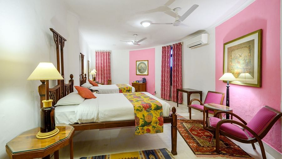 Hill Fort-Kesroli 14th Century Alwar - View of the Rawal Mahal room with twin beds, an air-conditioner and paintings hung on walls
