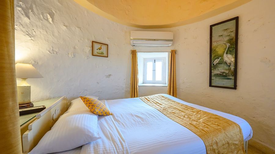 Hill Fort Kesroli 14th Century Alwar - interior view of the Saras Mahal featuring a queen size bed, white walls and yellow-coloured ceiling
