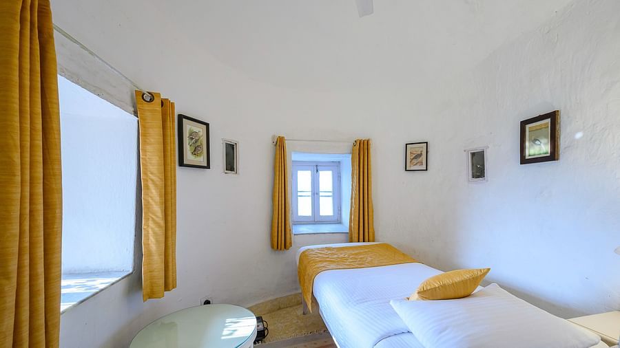 Hill Fort Kesroli 14th Century Alwar - interior view of the Teetar Mahal - Pool View with a single bed, a coffee table and yellow curtains 