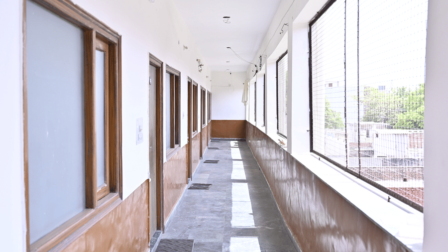  A hallway in a  hotel with open glass windows at one side and doors to rooms at one side - Hotel Goverdhan, Agra