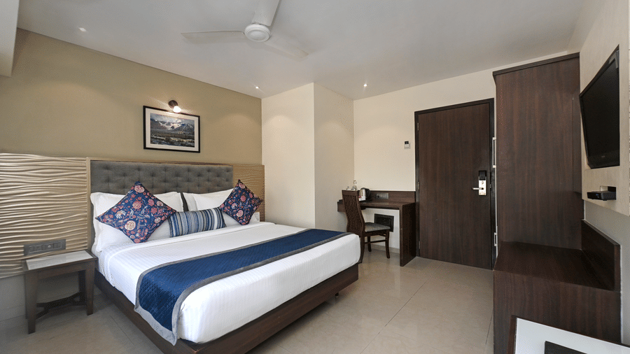 The Superior Room of Hotel Le Grande featuring a double bed, tiled flooring, a ceiling fan, and a wooden cupboard.
