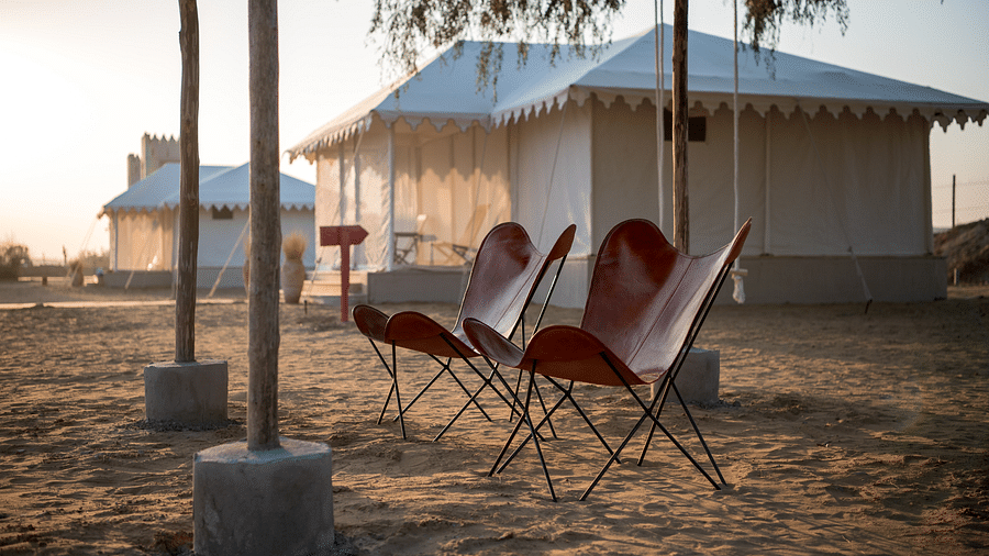Foldable chairs are placed on the sand near the accommodations - Karwaan Jaisalmer