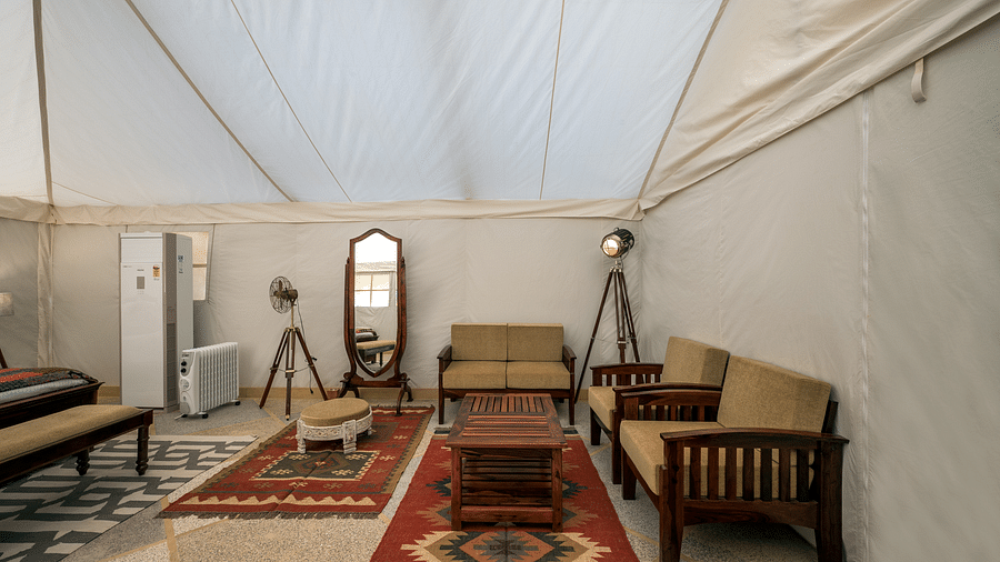 The interiors of the accommodations contain sofas, a teapoy and a mirror - Karwaan Jaisalmer