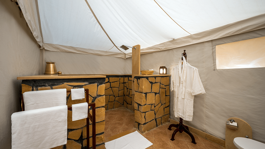The bathrobe and towels are hung on the clothes stand in the washroom - Karwaan Jaisalmer