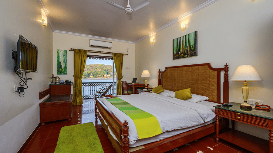 A double bed with balcony and marble side table in Cones - River View Room at neemranas three waters