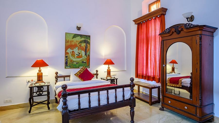 A double bed next to a lamp sitting on a side table with a wardrobe inside Maharaja Rajinder Singh room - The Baradari Palace