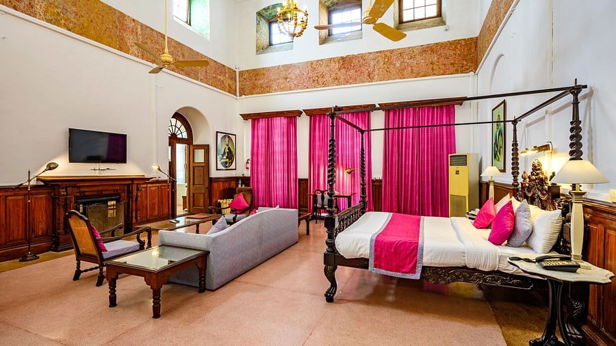A double bed with a sofa and single seat chair in front of the tv inside Raja Sardul Singh room - The Baradari Palace
