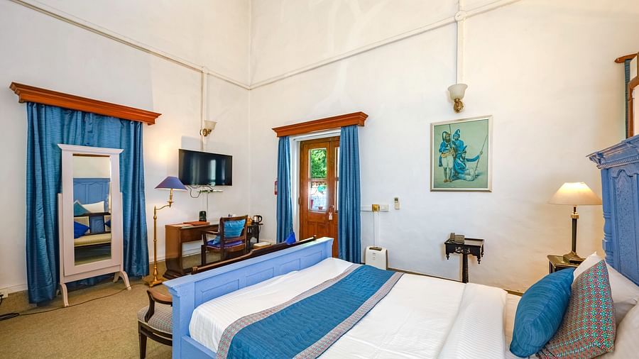An overview of the Maharani Mohinder Kaur room with a double bed, a mirror and a study table - The Baradari palace