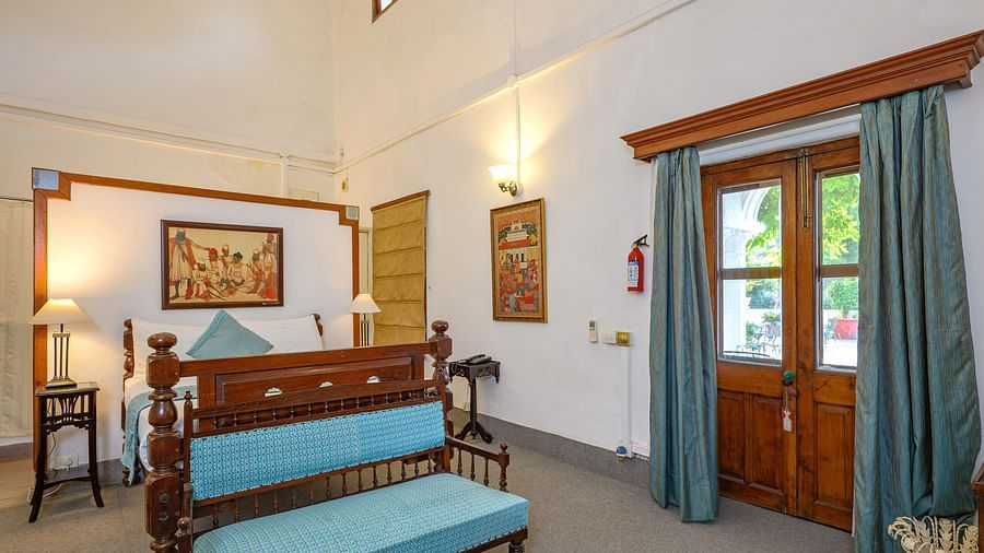 A double bed with a sofa in front and a painting hanging from above the headrest inside Maharani Bakhtawar Kaur room - The Baradari Palace