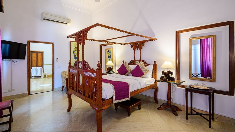 An overview of the Rani Fateh Kaur room with a double bed, mirror, and side tables - The Baradari palace