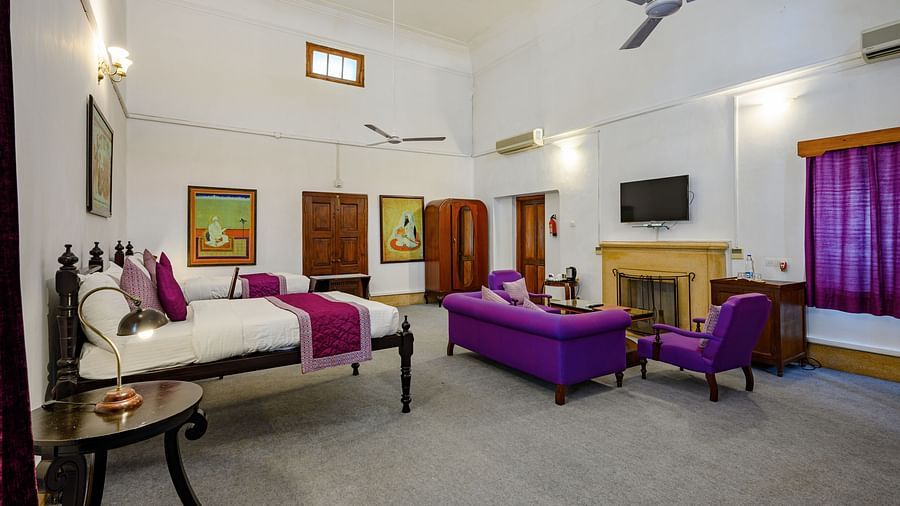 An overview of the Maharaja Karam Singh room with sofas, coffee table in front of the tv with king size bed on the side - The Baradari palace