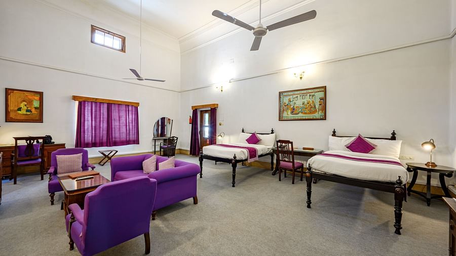 Twin beds, purple coloured sofas with a coffee table in the centre inside Maharaja Karam Singh room - The Baradari Palace