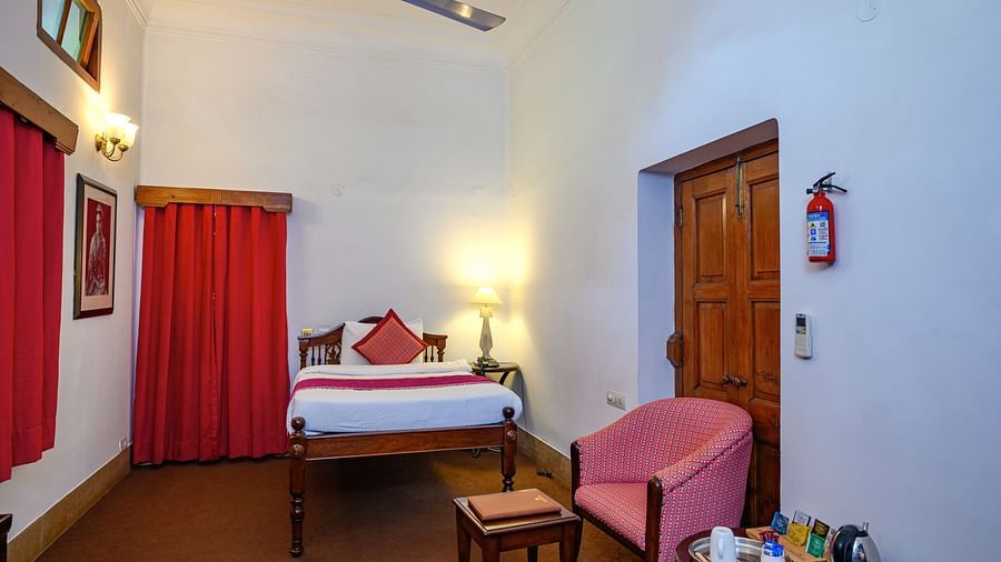 An overview of the Maharajkumari Surinder Kaur room with a double bed, a chair and a small table - The Baradari palace