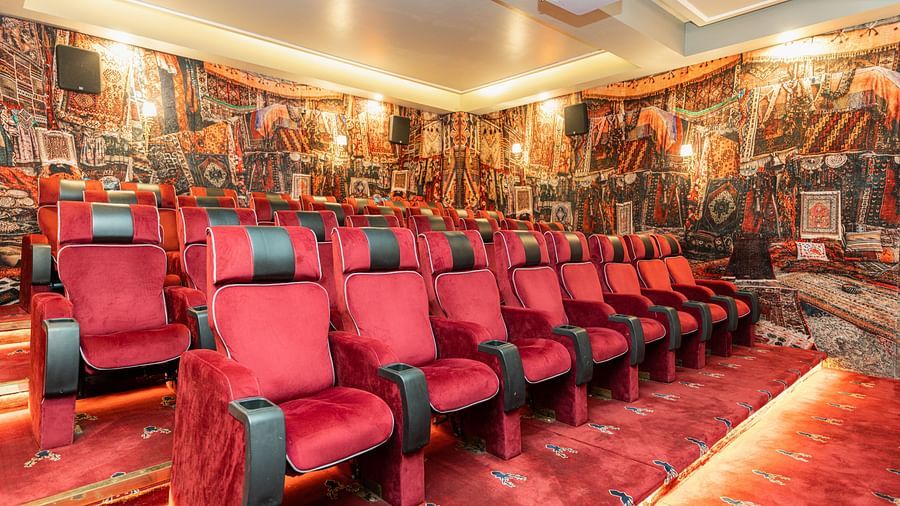 A theatre with reclining red chairs in ambient lighting - The Manor Luxury Hotel, Shimla